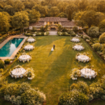 Vista aérea de fazenda com jardim piscina e casal de noivos no centro ao entardecer