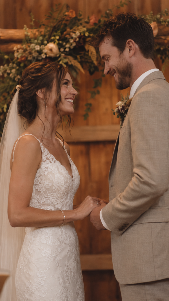Casal em decoração de casamento rústico com expressão emocionada em formato vertical