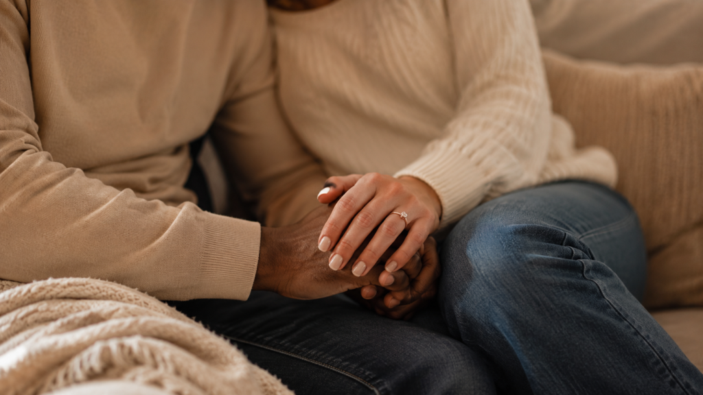 mãos de um casal entrelaçadas em casa em clima íntimo antes do pedido de casamento